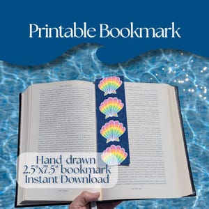 Op de afbeelding: Een donkerblauwe bladwijzer met vier regenboogkleurige schelpillustraties, geplaatst op een open boek. De bladwijzer meet 6,35 cm bij 19,05 cm. De tekst Printable Bookmark en Hand-drawn 2.5"x7.5" bookmark Instant Download is zichtbaar.