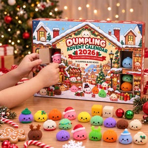Op de afbeelding: Een rechthoekige Dumpling Adventskalender 2026 doos met 24 verrassingsvakjes, voorzien van een feestelijke dorpsillustratie. De set bevat diverse kleine, kleurrijke, lachende knoedelvormige figuurtjes met kerstaccessoires.