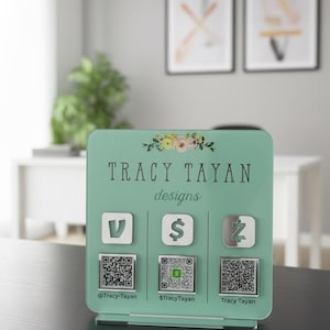 Custom acrylic QR code sign with three QR codes, gold social media icons and personalized business branding, displayed on a reflective countertop