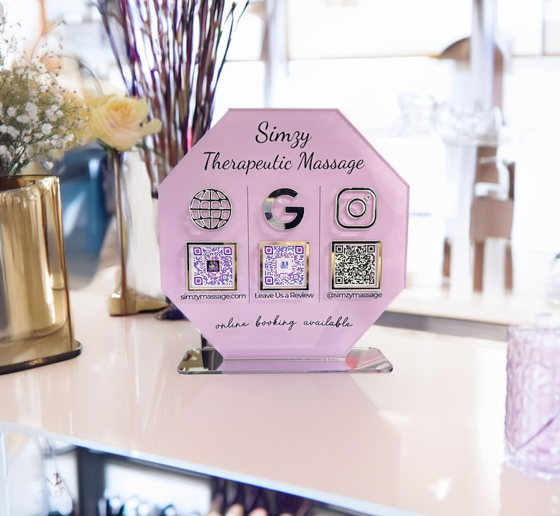 Custom acrylic QR code sign with three QR codes, gold social media icons and personalized business branding, displayed on a reflective countertop
