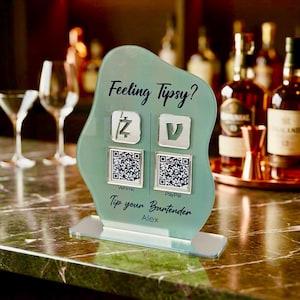Custom acrylic QR code sign with two QR codes, gold social media icons and personalized business branding, displayed on a reflective countertop