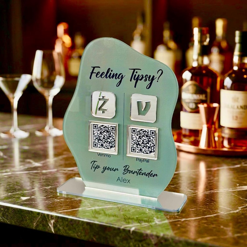 Custom acrylic QR code sign with two QR codes, gold social media icons and personalized business branding, displayed on a reflective countertop