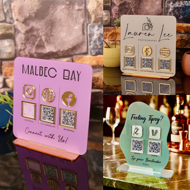 Custom acrylic QR code sign with three QR codes, gold social media icons and personalized business branding, displayed on a reflective countertop