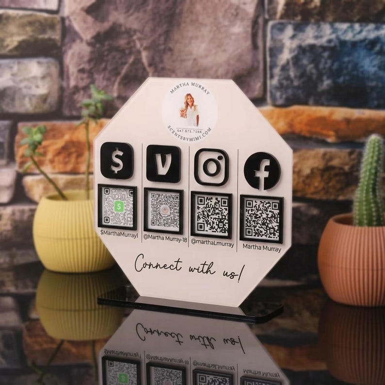 May include: An octagonal white acrylic sign featuring a circular logo with a person's image, four black social media icons, and four corresponding QR codes. Below the icons, the text reads "Connect with us!" along with four social media handles.