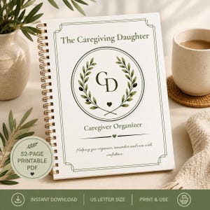 May include: A white spiral-bound notebook titled The Caregiving Daughter Caregiver Organizer. The cover features a green olive branch wreath surrounding the letters CD, a small heart, and the text Helping you organize, remember and care with confidence.