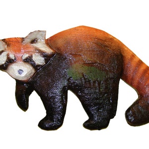 May include: A hand-painted wooden sculpture of a red panda. The sculpture is painted in shades of red, brown, and black, with a white face and black eyes. The red panda is standing on all fours, with its tail curled around its body.