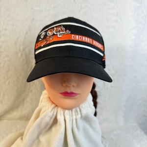 May include: Black baseball cap with the Cincinnati Bengals logo. The cap features the team's tiger mascot in orange and white stripes. The text "CINCINNATI BENGALS" is also visible on the cap.