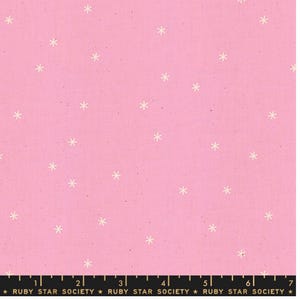 May include: A pink fabric featuring a scattered pattern of small, off-white six-pointed star shapes. A black measuring tape is visible at the bottom edge, showing measurements in inches from 0 to 7, with the text RUBY STAR SOCIETY printed.