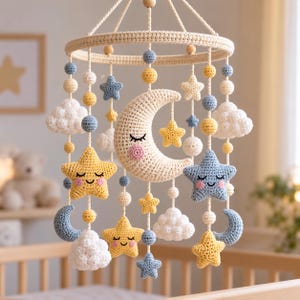 May include: A hanging nursery mobile featuring crocheted elements in soft pastel colors. The design includes a central cream-colored crescent moon with a face, surrounded by yellow and blue stars with faces, white clouds, and small round beads.