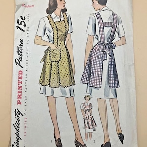 Könnte beinhalten: Ein Vintage-Schnittmusterumschlag von Simplicity, Nummer 4868, Größe Medium. Die Vorderseite zeigt Illustrationen eines weißen kurzärmeligen Kleides, das mit einer gelben, gepunkteten Schürze oder einer blau-weiß karierten Schürze getragen wird.