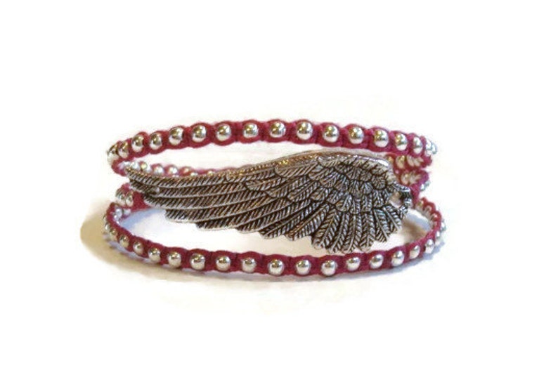 May include: A red leather wrap bracelet with silver beads and a silver angel wing charm.