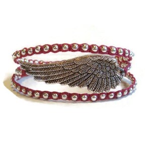 May include: A red beaded wrap bracelet with a silver angel wing charm.