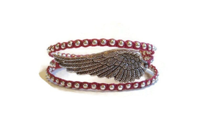 May include: A red beaded wrap bracelet with a silver angel wing charm.