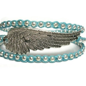 Puede incluir: Un brazalete de envoltura azul turquesa con cuentas plateadas y un dije de ala plateada.