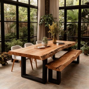 May include: A rectangular dining table and a matching bench, both featuring natural live-edge light wood tops and sturdy black metal U-shaped legs. Three light grey upholstered chairs with wooden legs are positioned around the table.