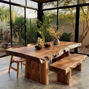 May include: A large rectangular dining table with a natural live edge and a matching wooden bench. The table is crafted from brown wood with visible grain patterns and features two thick slab legs. A wooden chair is positioned at the table end.