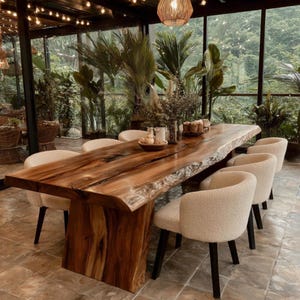 Puede incluir: Una mesa de comedor larga con un tablero de madera maciza de borde natural y una base de madera, rodeada por seis sillas tapizadas de color crema con patas negras. La mesa presenta un veteado de madera prominente y un acabado pulido.