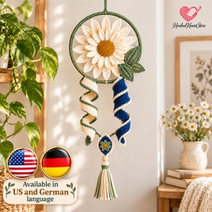 May include: A crochet wall hanging featuring a large white flower with a yellow center inside a green circular frame. Two spiral crochet ribbons in cream and navy blue hang below, connected to a small floral motif and a multi-colored yarn tassel.