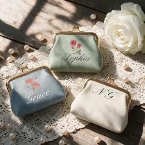 May include: Three coin purses with gold-tone metal kiss-lock clasps. One sage green purse features a red rose graphic and the name Sophia. One blue purse features a pink flower graphic and the name Grace. One cream purse features the initials NG.