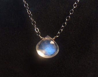 May include: A silver chain necklace with a teardrop-shaped moonstone pendant. The moonstone is iridescent and has a blue sheen.