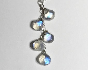 May include: A silver chain necklace with a teardrop-shaped moonstone pendant. The pendant is made up of five smaller moonstones, each with a different iridescent blue and white color.