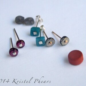 May include: A set of six earrings with various colored glass and metal accents. The earrings are displayed on a white surface.