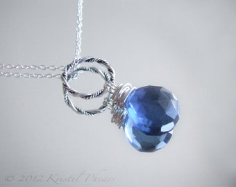 May include: A silver chain necklace with a pendant featuring two intertwined silver rings and a large blue gemstone.