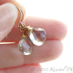 May include: Gold wire wrapped earrings with clear faceted teardrop shaped gemstones.