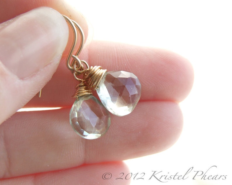May include: Gold wire wrapped earrings with clear faceted teardrop shaped gemstones.