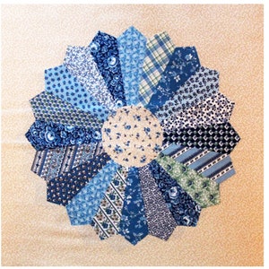 May include: A blue and white patchwork quilt with a circular design. The center of the quilt is a cream-colored fabric with a floral pattern. The quilt is made up of various blue and white fabrics with different patterns.