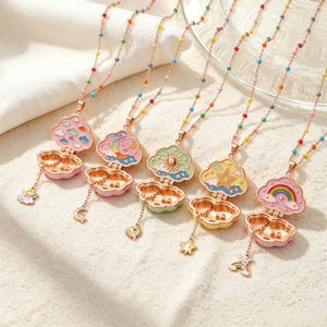 May include: Five gold-tone metal necklaces featuring openable cloud-shaped lockets with colorful enamel designs including a rainbow, star, sun, moon, and clouds. Each chain is accented with small multicolored beads and a dangling charm.