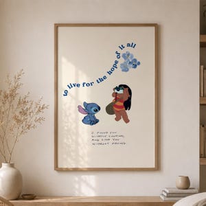 Può includere: Una stampa artistica da parete rettangolare in una cornice di legno con un personaggio alieno blu e una ragazza con una fotocamera. Il testo recita "to live for the hope of it all" e "I FOUND YOU WITHOUT LOOKING, AND LOVE YOU WITHOUT TRYING." Fiori blu inclusi.
