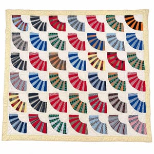 Puede incluir: Una colcha cuadrada con una cuadrícula de cuarenta y dos parches de tela en forma de abanico con diversos tejidos de cuadros, rayas y estampados. Los bloques están sobre un fondo color crema con un borde a juego y textura acolchada.