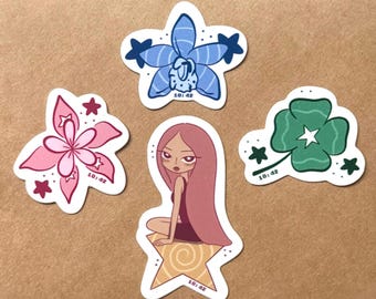 May include: A set of four die-cut stickers featuring a blue orchid, a pink flower, a green four-leaf clover, and a character with long pink hair sitting on a yellow star. Each sticker includes small dark stars and the printed text 10:42.