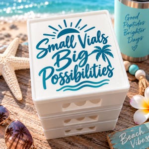 Peut inclure: Un conteneur de rangement carré blanc à trois niveaux empilés, avec une impression graphique bleue indiquant Small Vials Big Possibilities avec un soleil, un palmier et des vagues. Le conteneur présente des découpes festonnées sur chaque niveau.