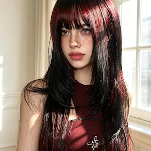May include: A long, layered wig featuring straight black hair with vibrant red highlights and bangs. The hair falls past the shoulders, showcasing a multi-tonal color palette with dark roots and bright red streaks throughout the length of the hair.