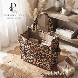 Puede incluir: Un bolso tote estructurado con un patrón de estampado de leopardo en marrón y negro. El bolso tiene dos asas superiores, bolsillos laterales y un interior abierto con una etiqueta rectangular marrón que dice DLIU FASHION. El interior es beige.