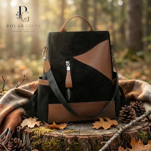 Puede incluir: Una mochila negra y marrón con asa superior, un bolsillo frontal vertical con cremallera y tirador marrón, y bolsillos laterales. El bolso presenta un diseño de bloques de color con paneles negros y detalles en marrón.