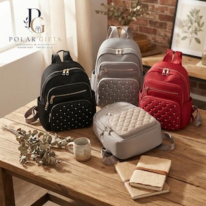 May include: Four backpacks in black, gray, red, and beige, each featuring a quilted front pocket with metallic studs, gold-tone zippers, and adjustable shoulder straps. The bags are arranged on a wooden surface with a ceramic mug and notebooks.
