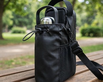 Peut inclure: Un sac porte-bouteille en tissu noir doté d'une fermeture à cordon, d'une poignée supérieure et d'une bandoulière réglable. Le sac comprend une poche latérale en filet et contient une bouteille d'eau métallique argentée avec une poignée noire.