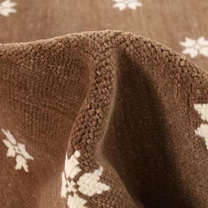 Handgjord matta i Oushak-stil i brunt och elfenbensfärgat ullmönster med ett minimalistiskt geometriskt mönster som liknar en stjärna och ett snöflinga.