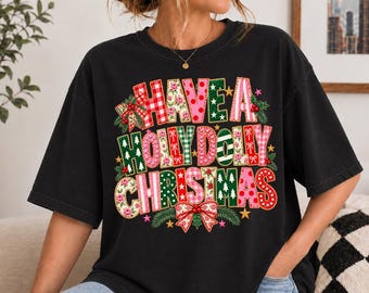 May include: A black short-sleeved t-shirt featuring the text "HAVE A HOLLY DOLLY CHRISTMAS" in large, multi-coloured block letters. The letters are decorated with various patterns including red gingham, pink polka dots, and green pine trees.