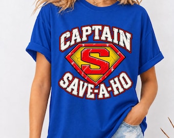 May include: A royal blue short-sleeved t-shirt featuring a graphic design with a yellow and red diamond-shaped emblem containing a large red letter S. The text CAPTAIN is arched above the emblem and SAVE-A-HO is arched below in white.