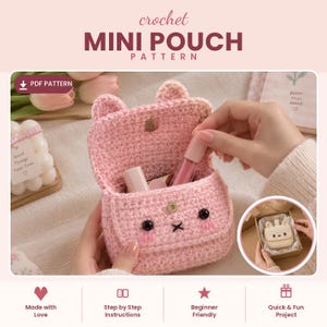 Könnte beinhalten: Ein hellrosa gehäkeltes Mini-Täschchen mit einer Klappe, zwei kleinen Ohren, schwarzen Perlenaugen, einem gestickten Mund und rosa Wangen. Das Täschchen hat einen goldenen Druckknopfverschluss und enthält zwei kleine Kosmetiktuben im Hauptfach.