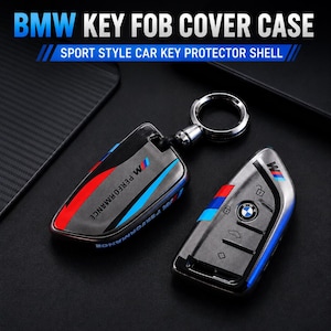 May include: A BMW key fob cover case with a sport style car key protector shell. The black cover features red and blue stripes and the text M PERFORMANCE. A metal ring is attached to the top. The set includes a black car key with buttons.