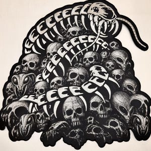 May include: A black and white embroidered patch featuring a large centipede-like creature winding through a pile of human skulls and alien heads. The text EEEEEEEEE is integrated into the creature's body, which has many legs.