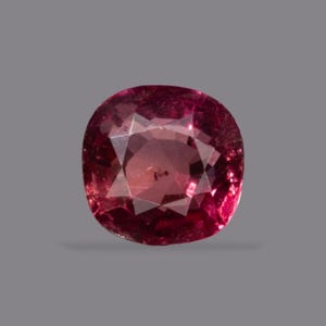 Peut inclure: Une pierre précieuse taille coussin d'une teinte rose rougeâtre profonde avec une surface à facettes. La pierre présente une structure interne claire avec de multiples facettes triangulaires et trapézoïdales qui reflètent la lumière.