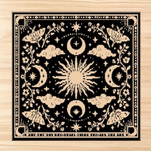 Puede incluir: Un textil cuadrado en negro y beige que presenta un sol central rodeado por cuatro lunas crecientes, nubes y polillas. El dise&ntilde;o incluye enredaderas florales intrincadas y estrellas dispuestas en un patr&oacute;n sim&eacute;trico con un borde decorativo.