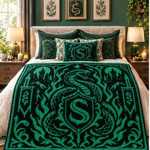 Könnte beinhalten: Eine dunkelgrüne und schwarze Strickdecke mit einem großen zentralen Schlangenemblem und dem Buchstaben S in einem Wappenschild. Die Decke zeigt komplizierte gotische Muster, darunter Burgsilhouetten und verzierte Rankenbordüren.