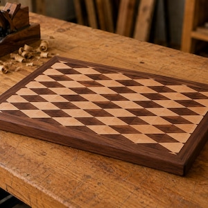 Op de afbeelding: Een rechthoekige houten snijplank met een geometrisch ruitpatroon gemaakt van afwisselende lichte en donkere houttinten. De plank heeft een massieve donkerhouten rand die het centrale inlegontwerp omlijst en een glad oppervlak.